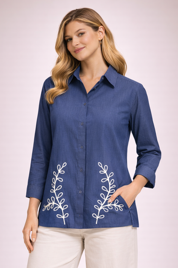 Woman wearing a blue shirt with white floral embroidery on a light pink background